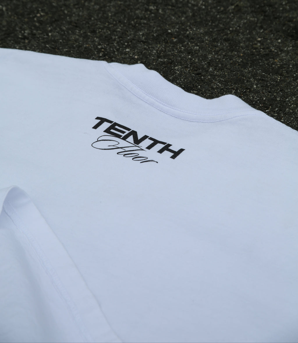 White t-shirt with 'Tenth Floor' logo on a textured black surface